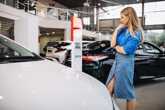 Woman looking at a white car in a car showroom