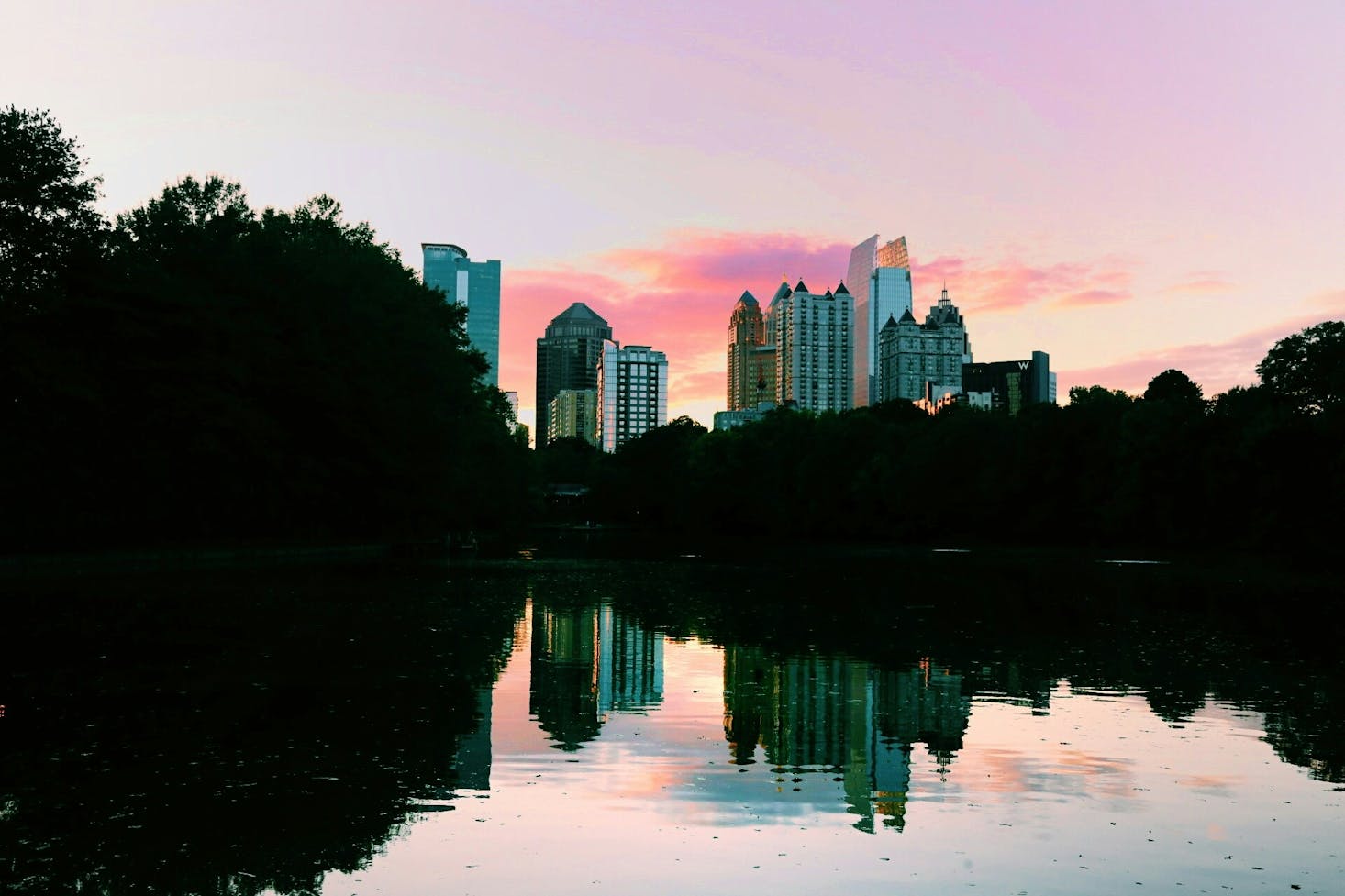 Sunset in Atlanta at Piedmont Park with the tall buildings of downtown mirrored in the calm water