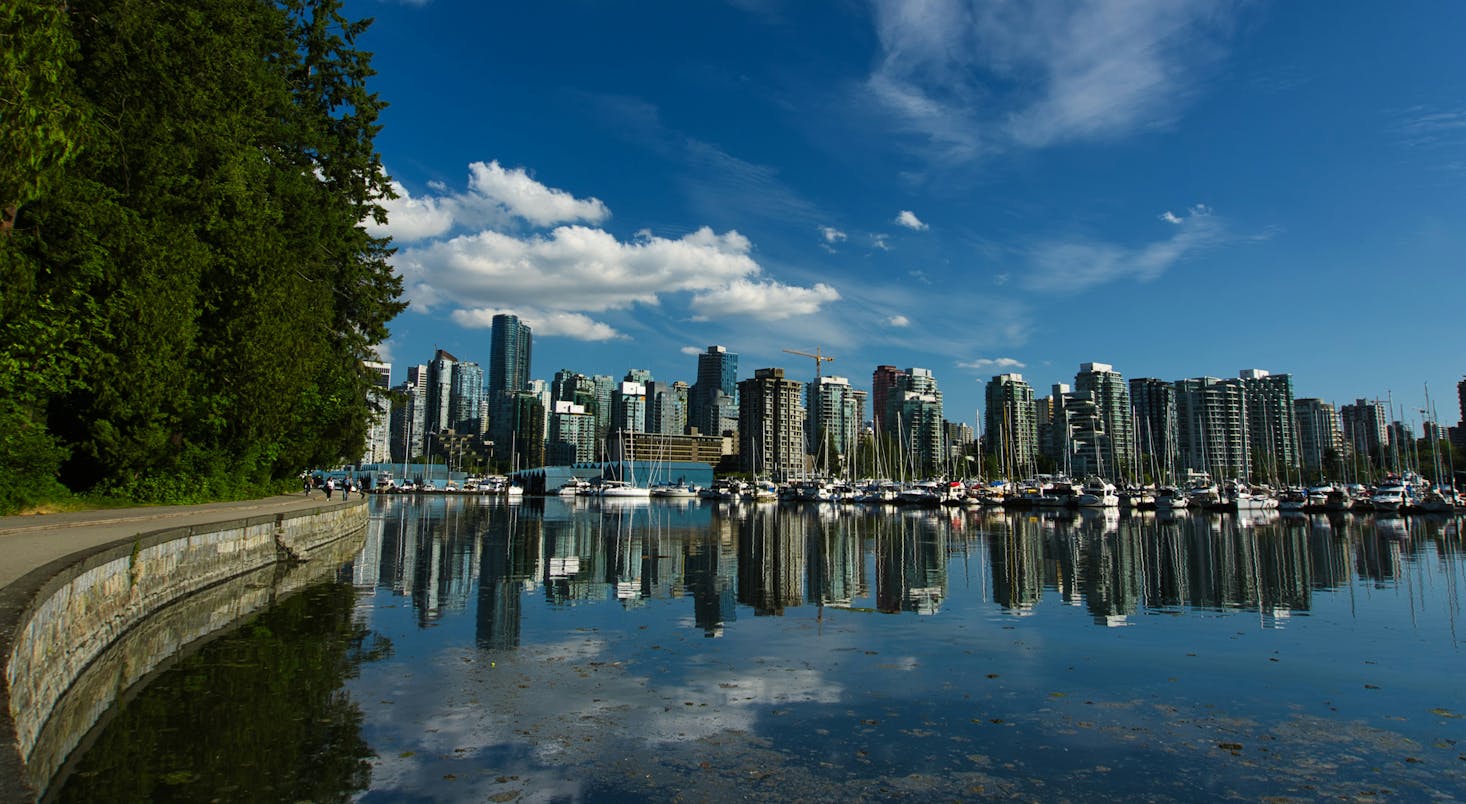 The Stanley Park Seawall with distant downtown buildings and moored boats