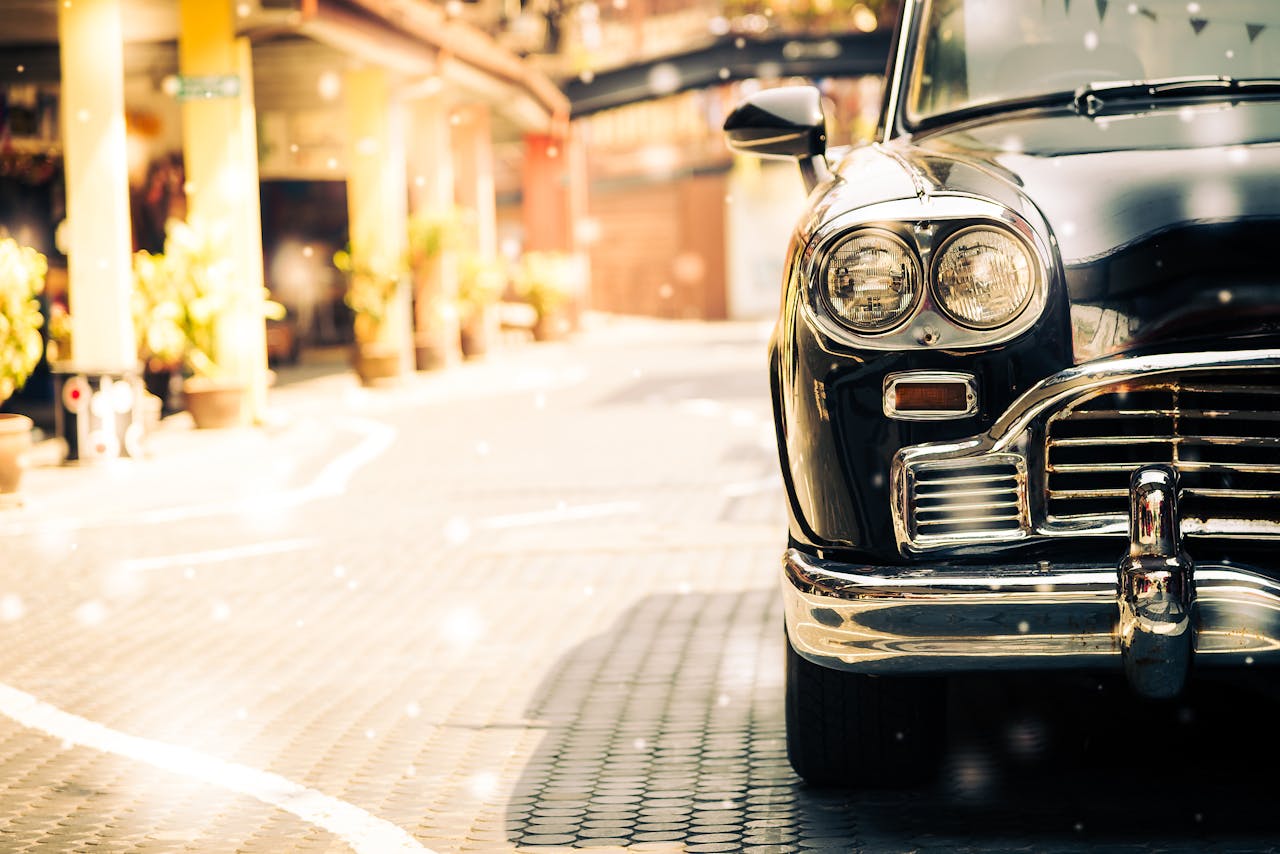 Old black vintage car on a sunny cobblestone street