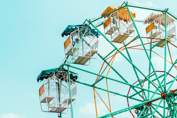 A colorful Ferris wheel with intricate floral designs on its cabins set against a bright blue sky