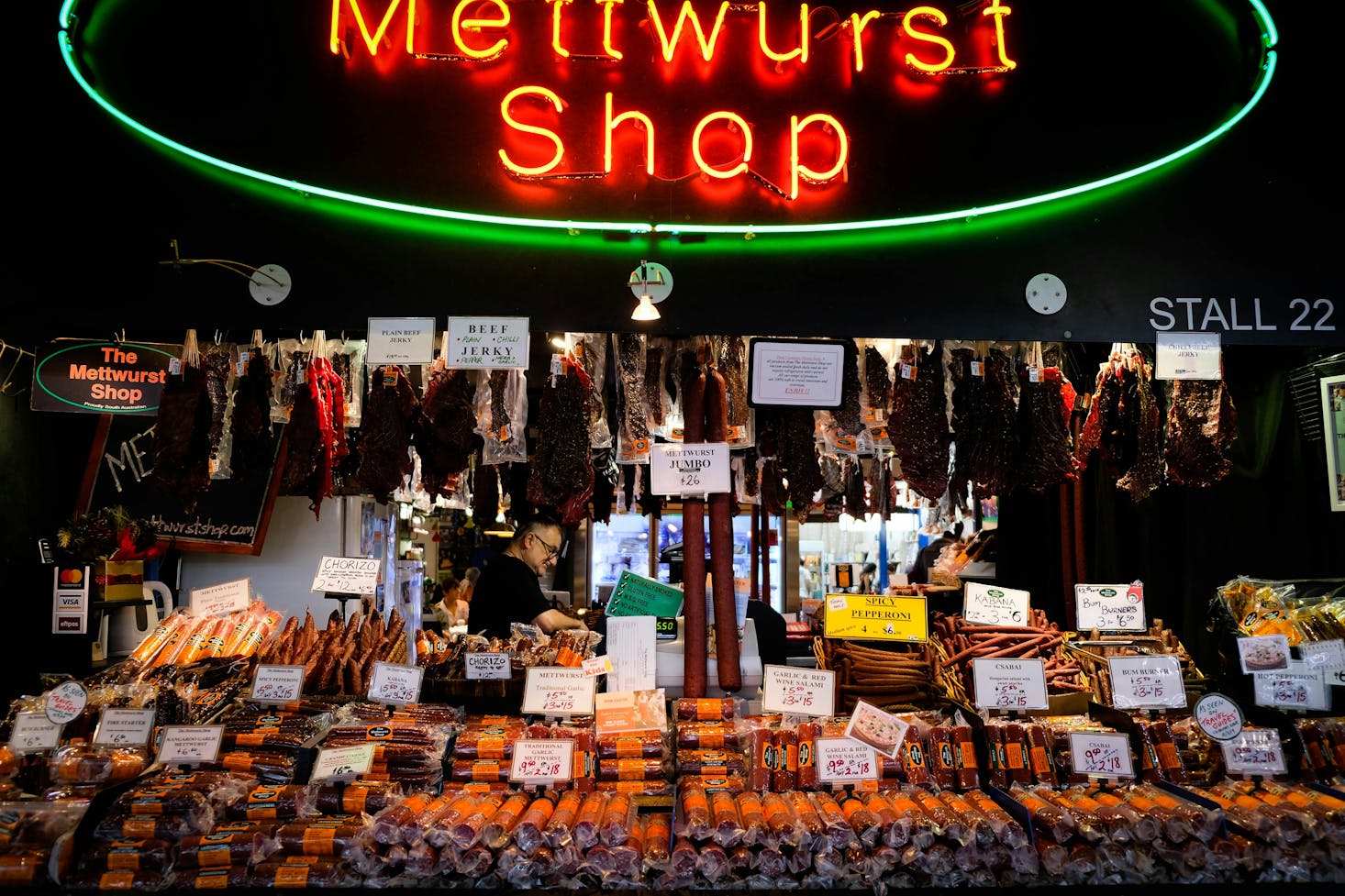 A neon red "Mettwust Shop" sign in front of various sausages at the Adelaide Central Market