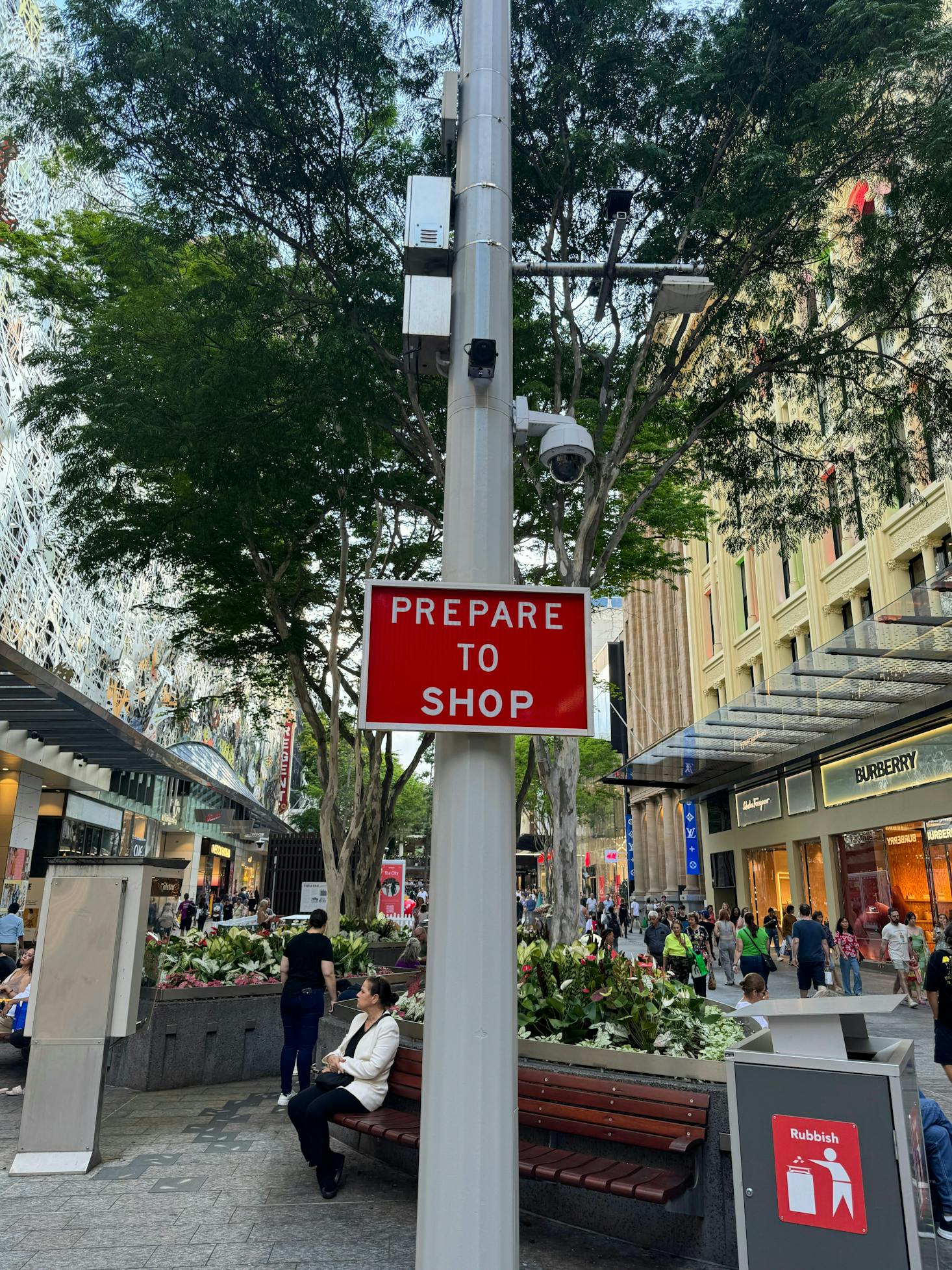 A red sign on a Brisbane lamppost that says "prepare to shop"