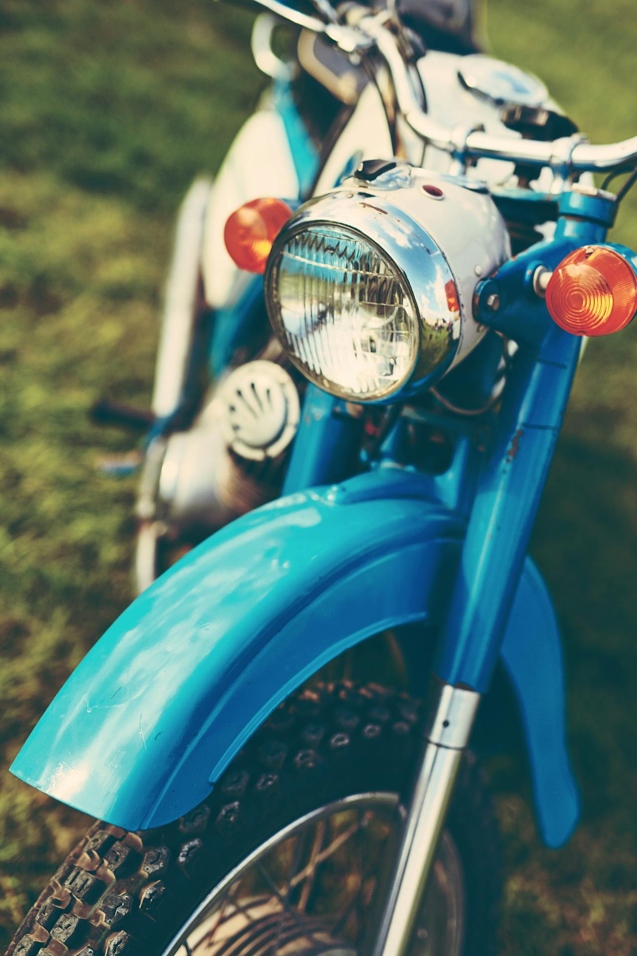 A close-up view of a vintage blue motorcycle with shiny chrome details