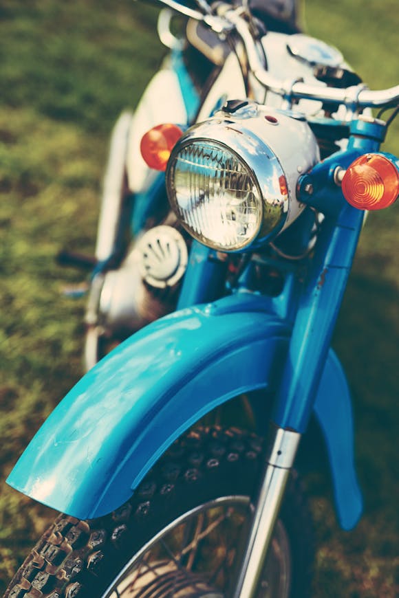 A close-up view of a vintage blue motorcycle with shiny chrome details