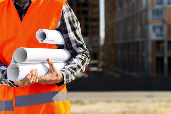 Close-up of a construction engineer holding plans in hands on a construction site