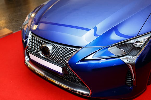 Curved blue sports car hood at an auto show showing an abstract reflection