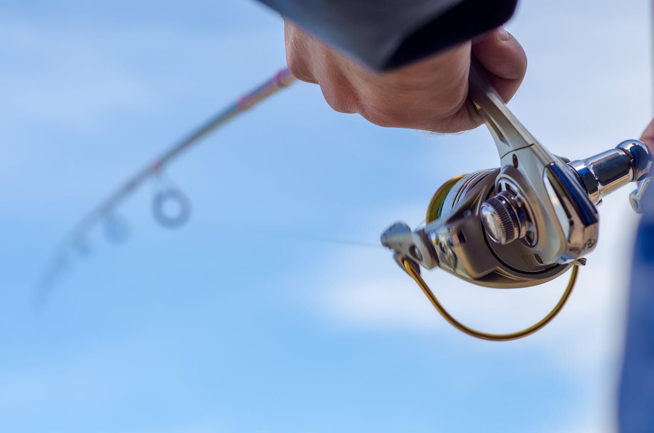 A close-up of an angler holding a fishing rod and reel, casting into the water at the Bassmaster Classic