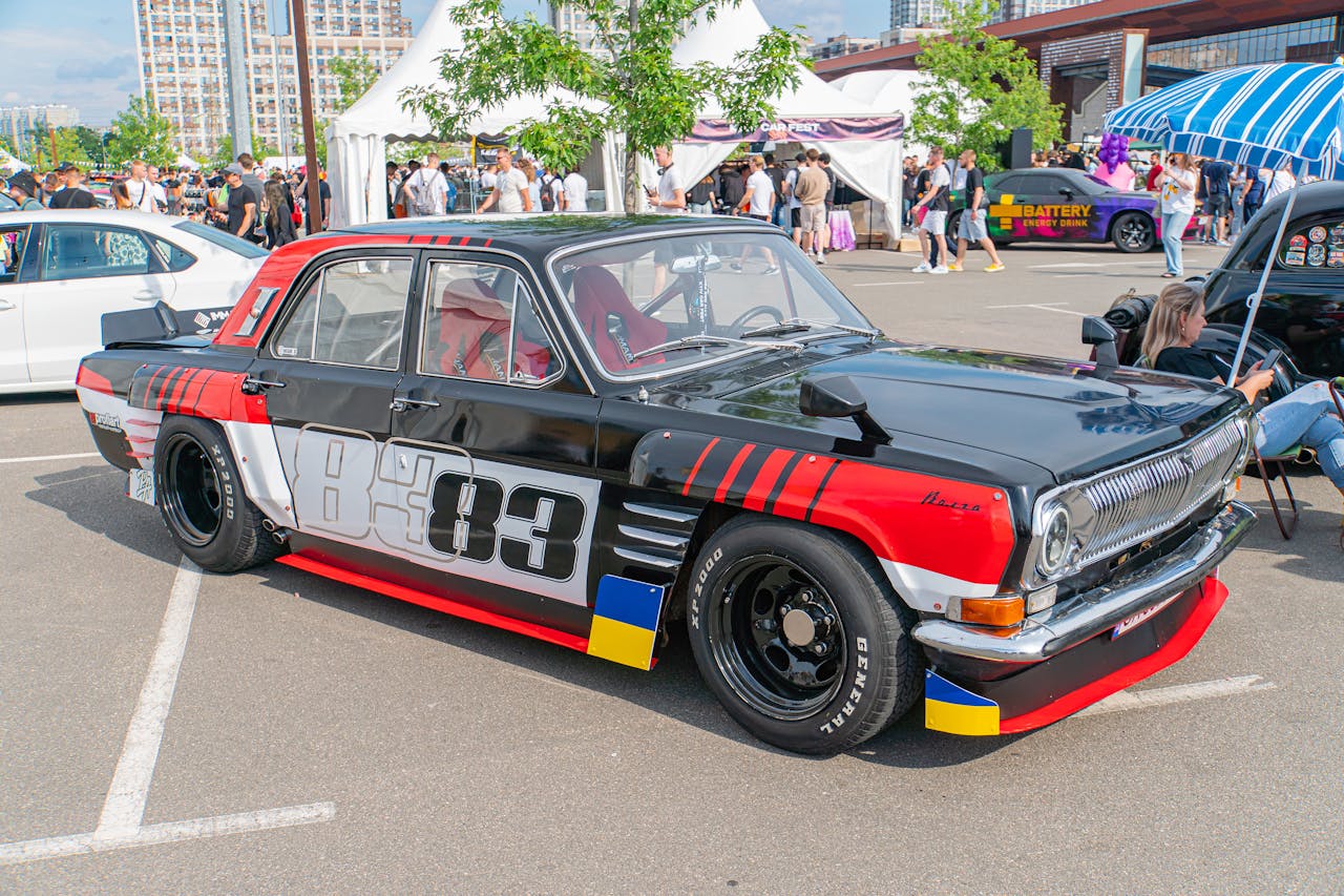 A vintage racing car parked outdoors featuring a predominantly black body with prominent white lettering and number graphics 