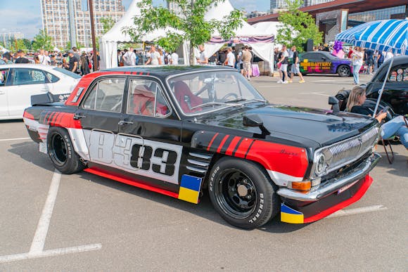 A vintage racing car parked outdoors featuring a predominantly black body with prominent white lettering and number graphics 