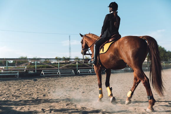 An equestrian riding a horse on dirt outdoors during the Kentucky Derby