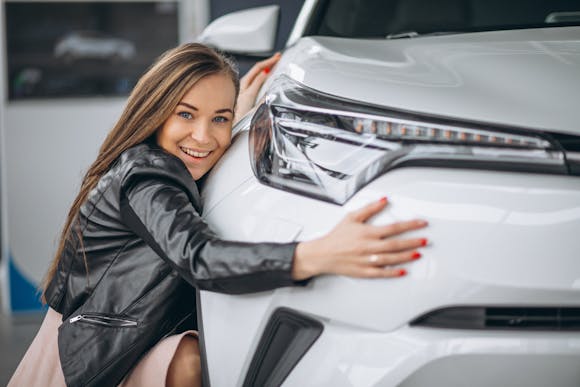 A woman hugging a modern car with a sleek design at Automobile Barcelona