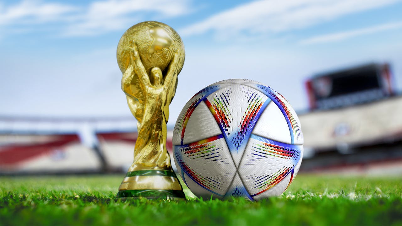 FIFA World Cup trophy next to a ball on a football field