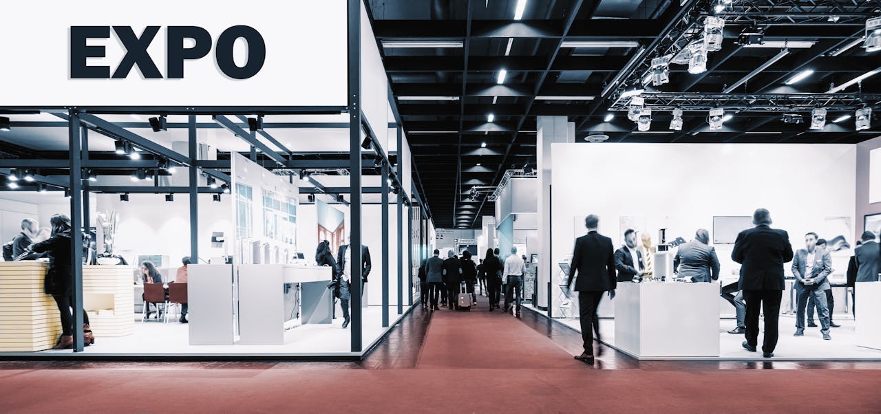 Crowd of people at a trade show booth with a banner and the text Expo