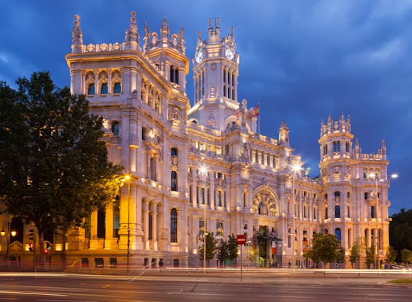 A landmark in Madrid called the Palace of Communication or Cibeles Palace at summer dusk