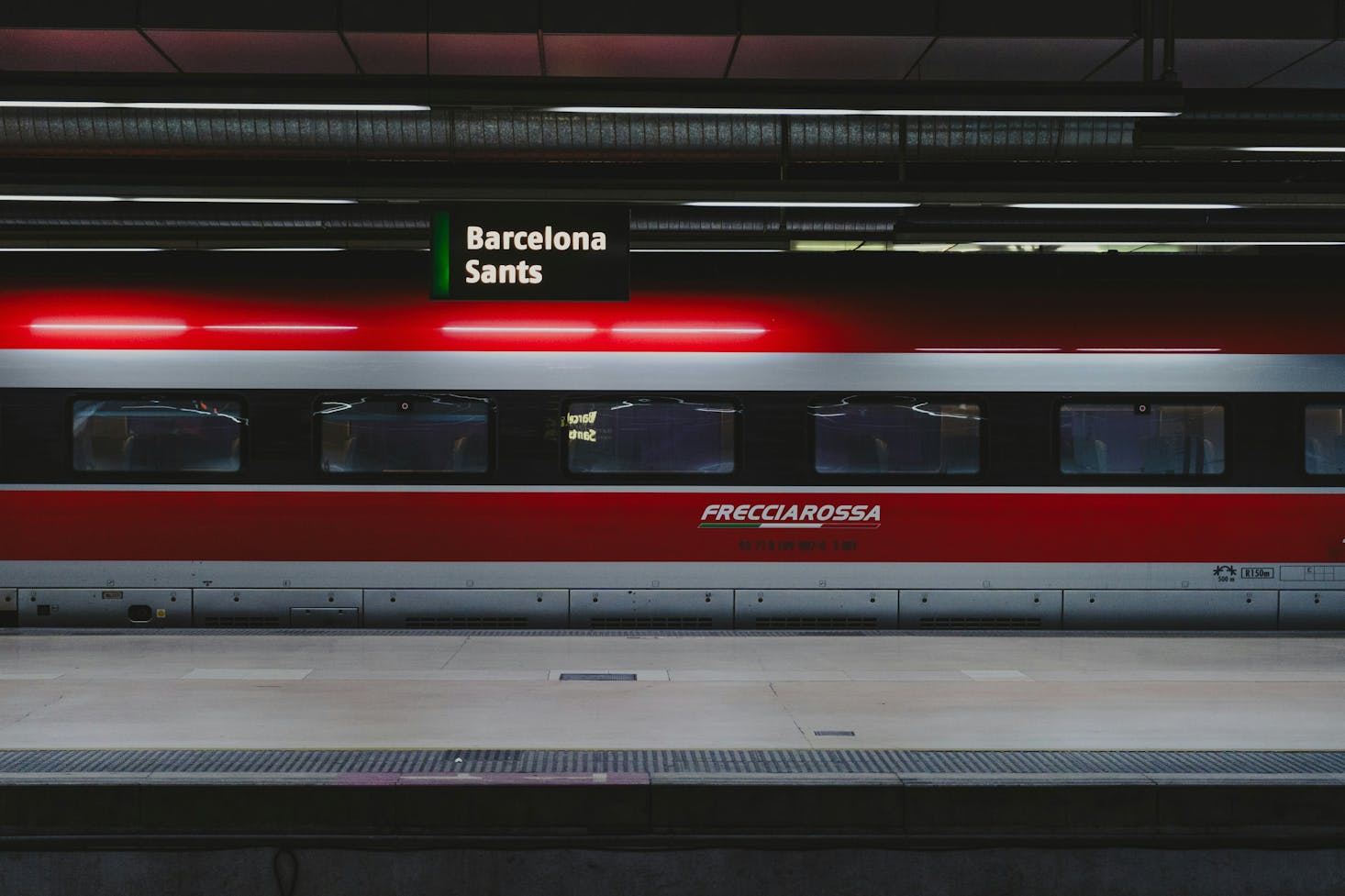 A red and silver train parked at the Barcelona Sants Train Station