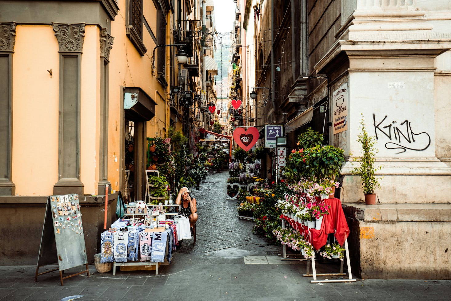 A narrow city street with shops and stalls in Naples