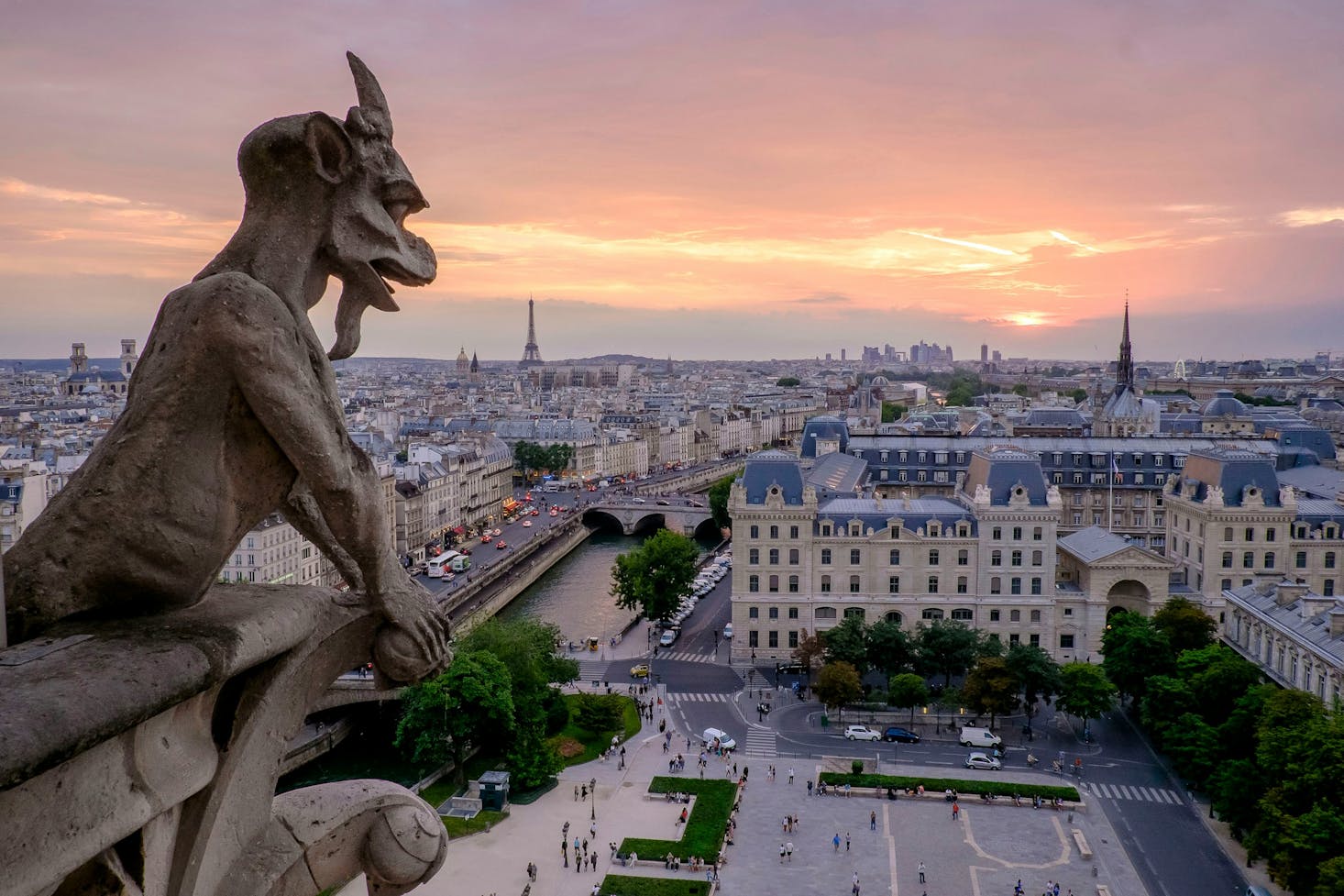 A Notre Dame gargoyle with the backdrop of Paris cityscape at sunset