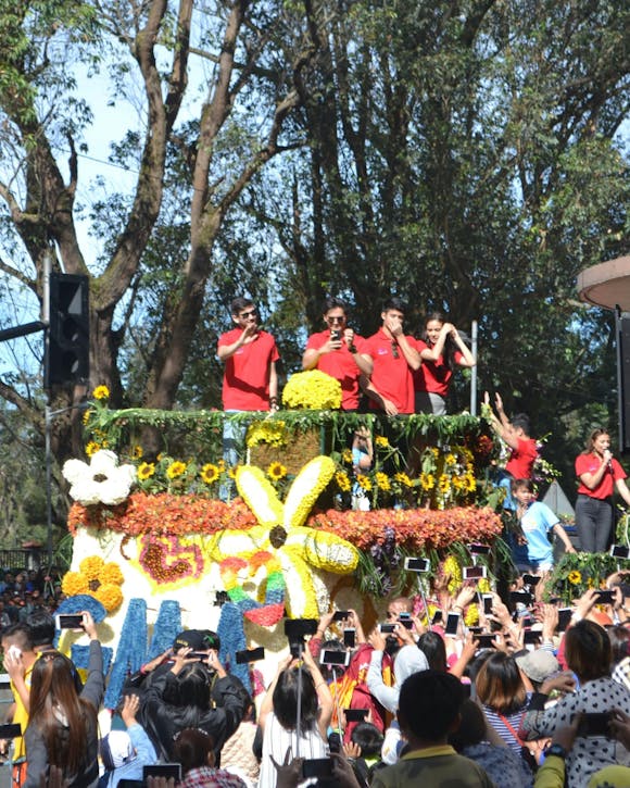 A decorated float surrounded by participants during a flower parade