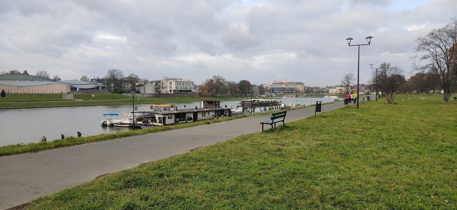 Park benches lining a paved path that follows a river