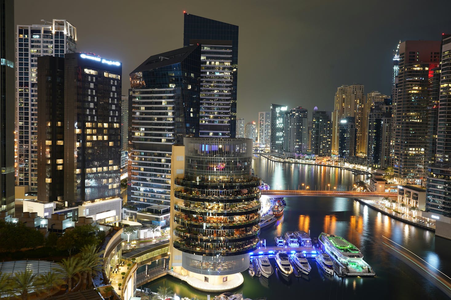 Boats moored in Dubai Marina at night with tall buildings all around