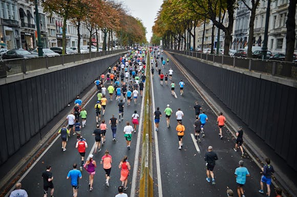 Marathon runners running on two wide city roads in the middle of a street