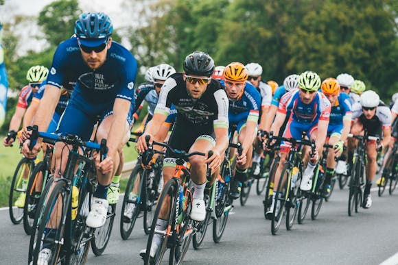 Cyclists energetically racing on a flat road with nature in the background during the Giro d'Italia