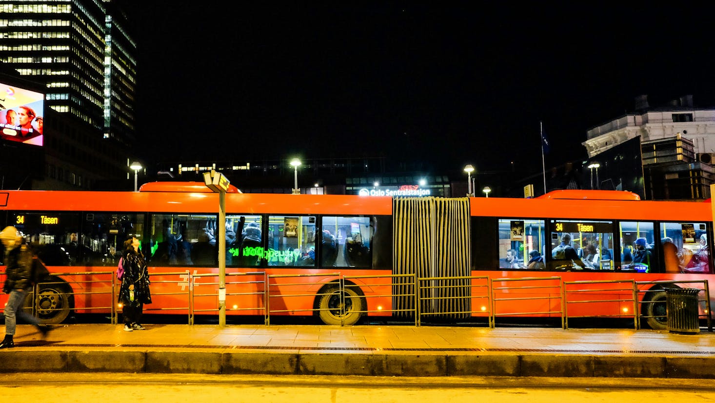 Two red buses sitting at Oslo Bus Terminal at night