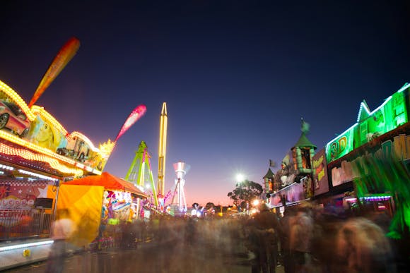 An amusement park at night with many lit up rides and stalls