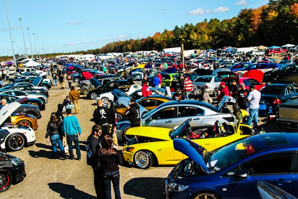 Carlisle Auction car meet featuring hundreds of cars with hoods up and car enthusiasts admiring them