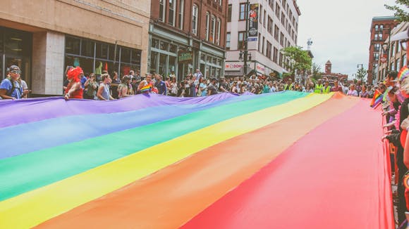 A giant rainbow flag held by Pride participants on the street during the Pride festival