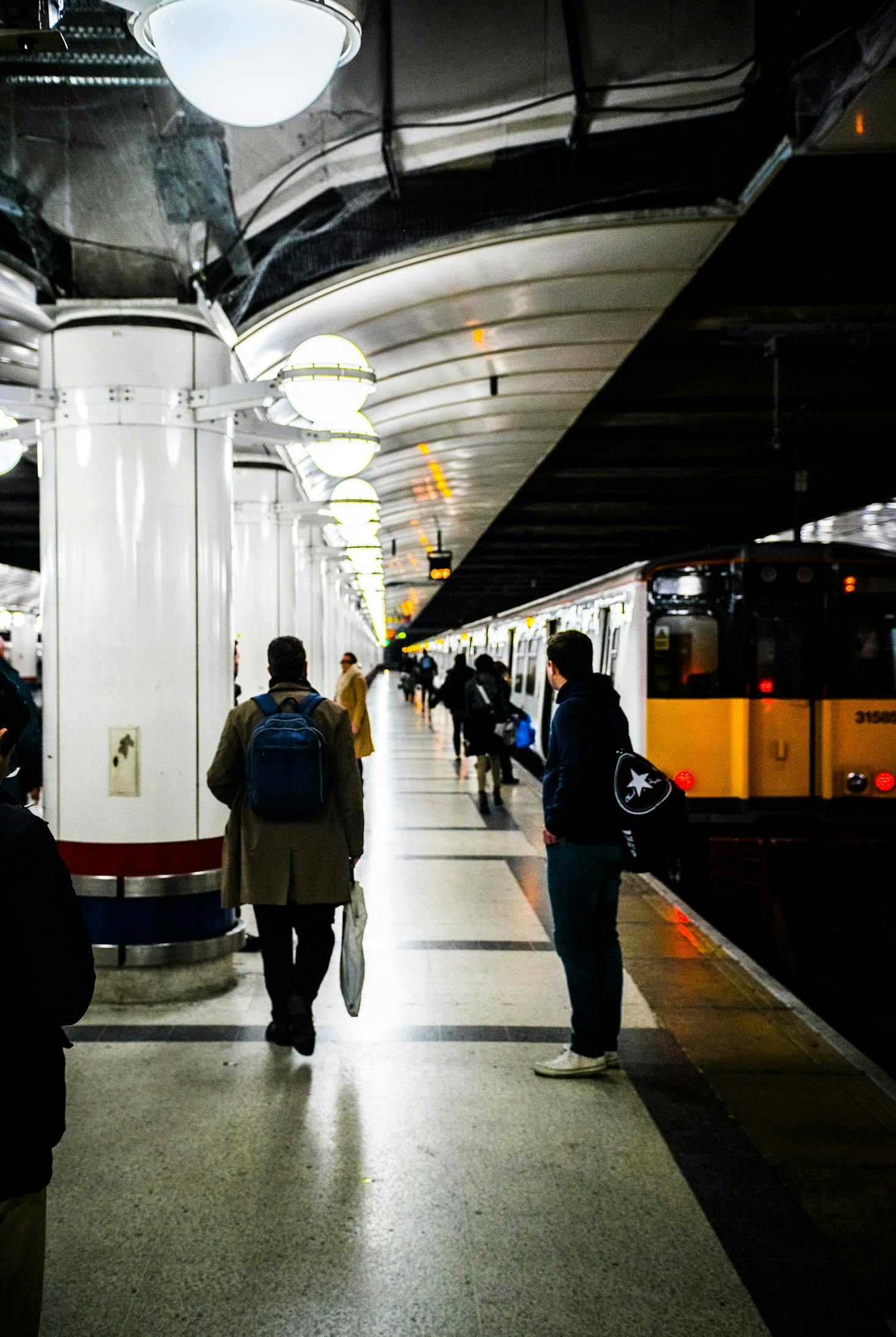 Los pasajeros esperan su tren bajo el resplandor de las luces de la plataforma en la Estación de Chamartín.