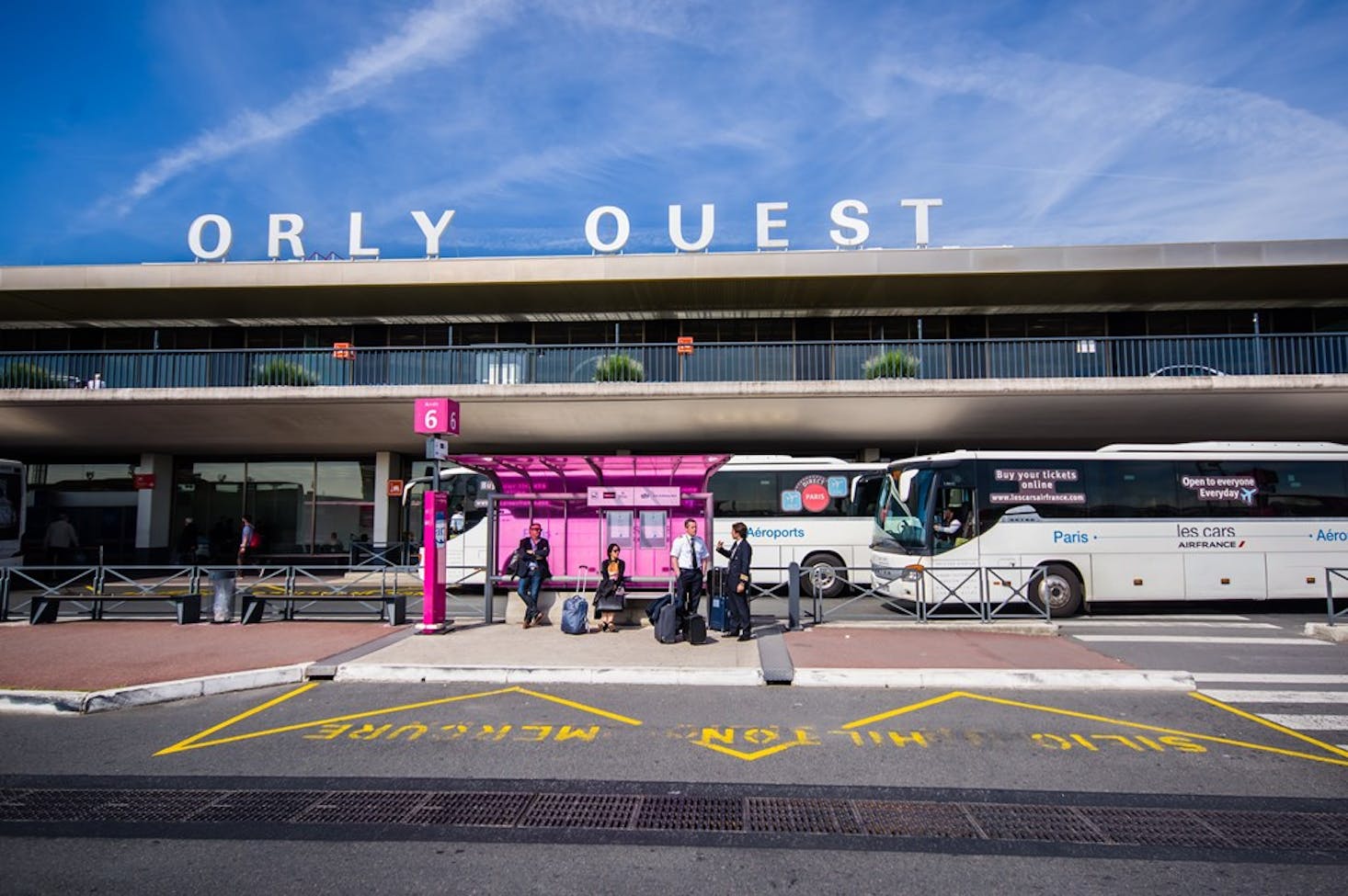 Orly Ouest, the west terminal of Orly Airport in Paris, France, with passengers waiting at a brightly colored bus stop.