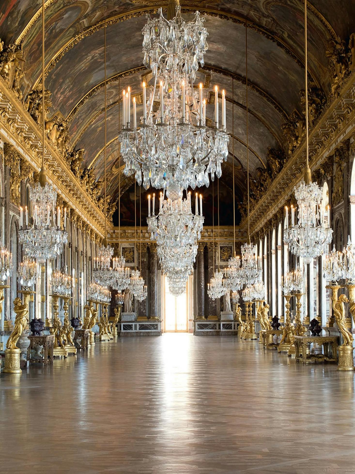 The Hall of Mirrors in the Palace of Versailles, adorned with intricate chandeliers and golden details.