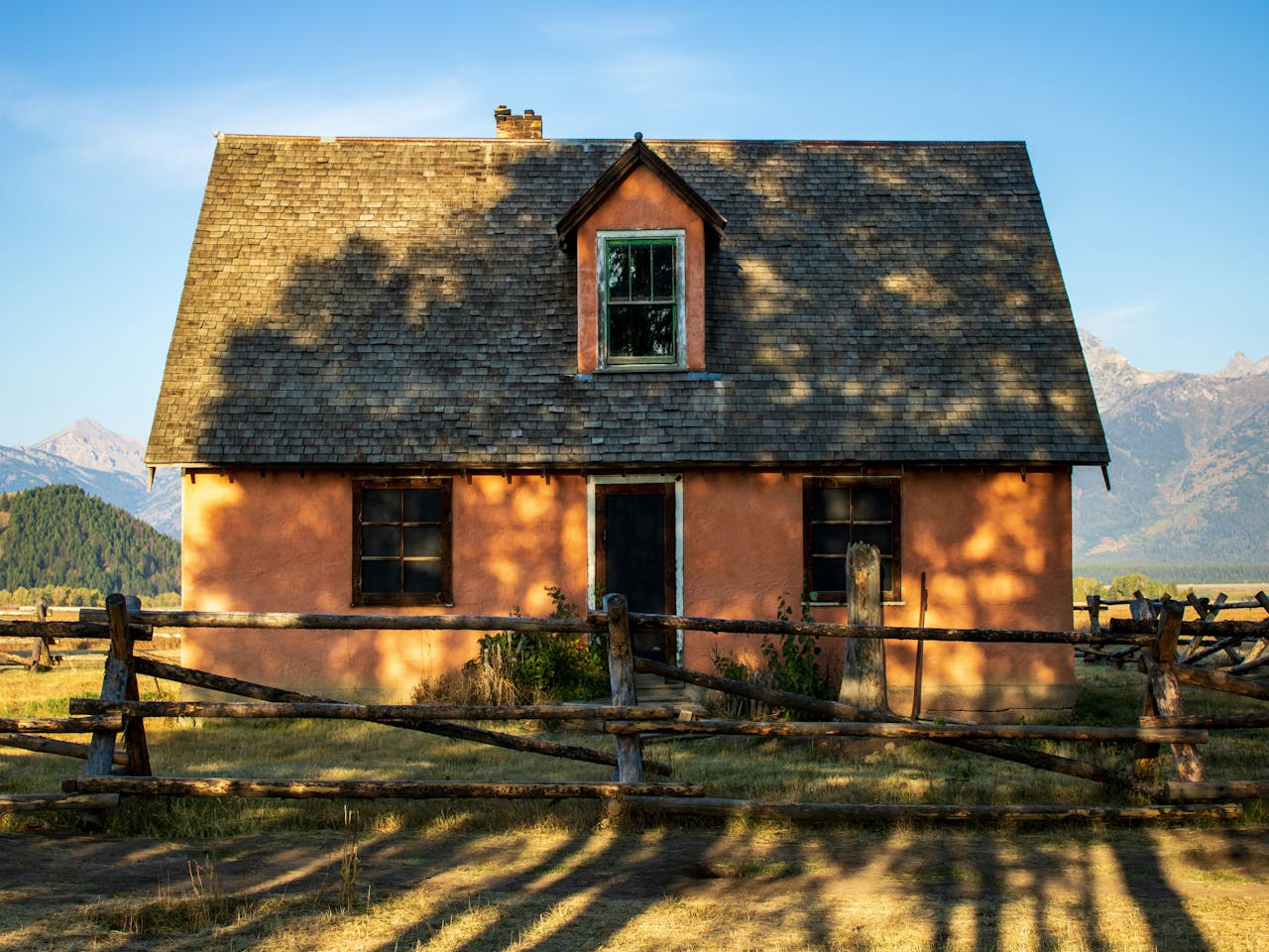 A quaint, rustic house with a shingled roof stands amidst a serene countryside in Jackson.