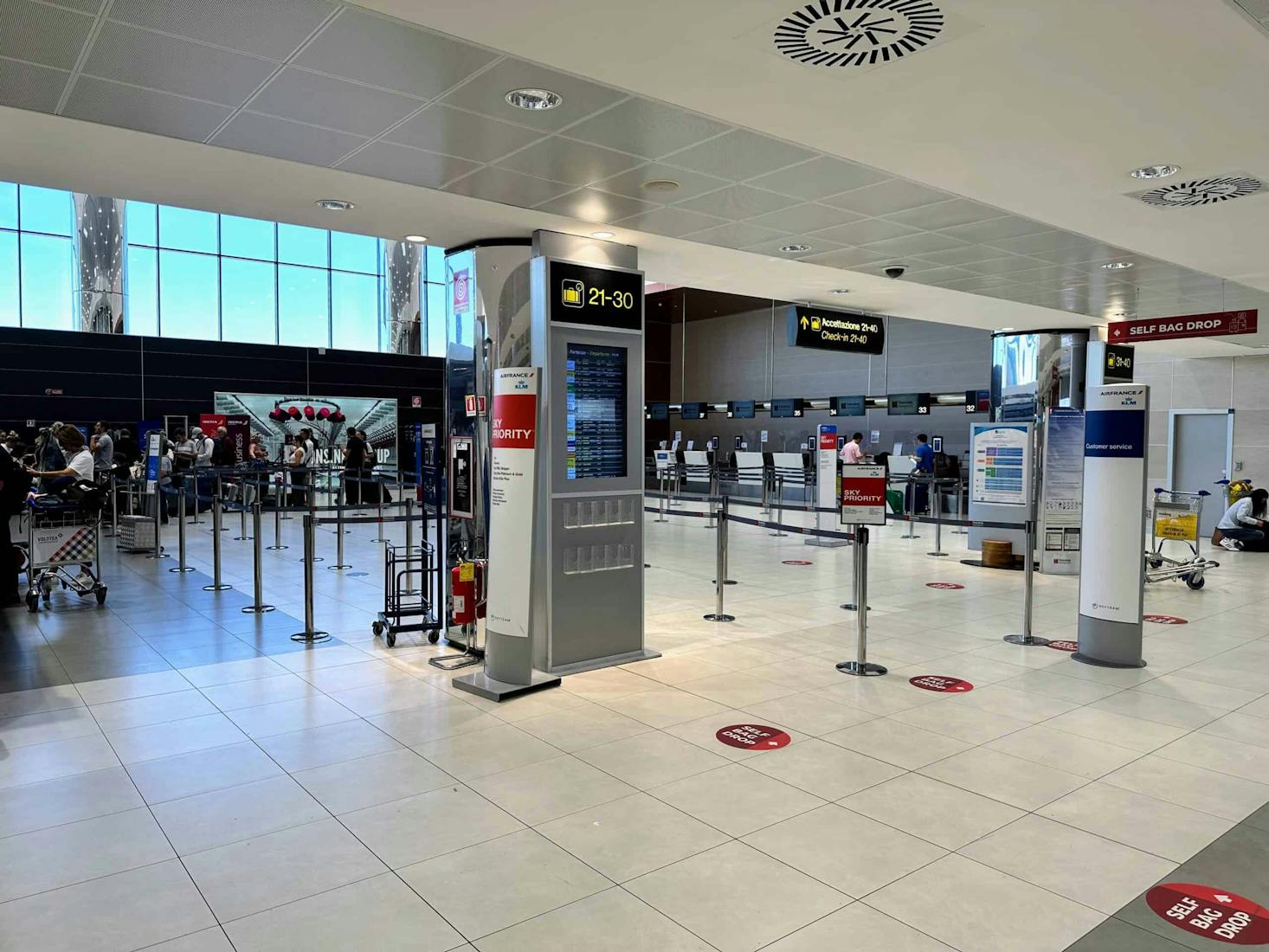 The check-in area at Florence Airport, featuring modern self bag drop kiosks, digital information displays.