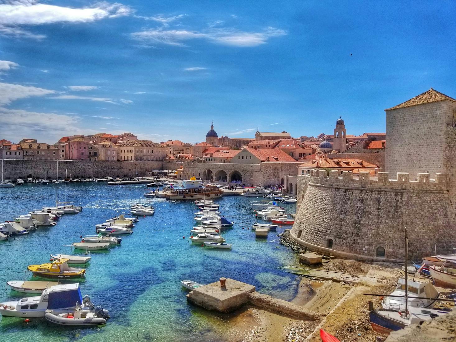 Picturesque view of Dubrovnik's old town port, featuring boats floating in clear blue water