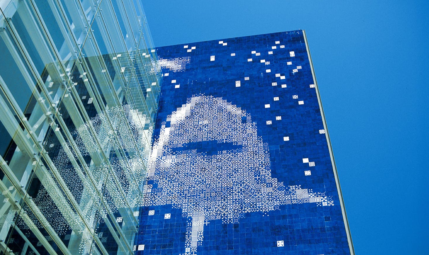 A tall building of the Lisbon Aquarium with a striking blue mosaic facade depicting a shark