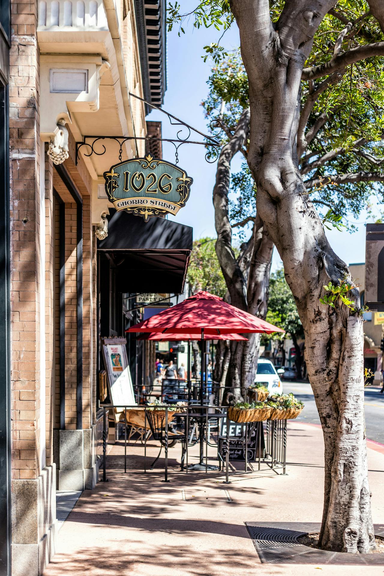 A charming sidewalk café with a vintage sign and red umbrella.