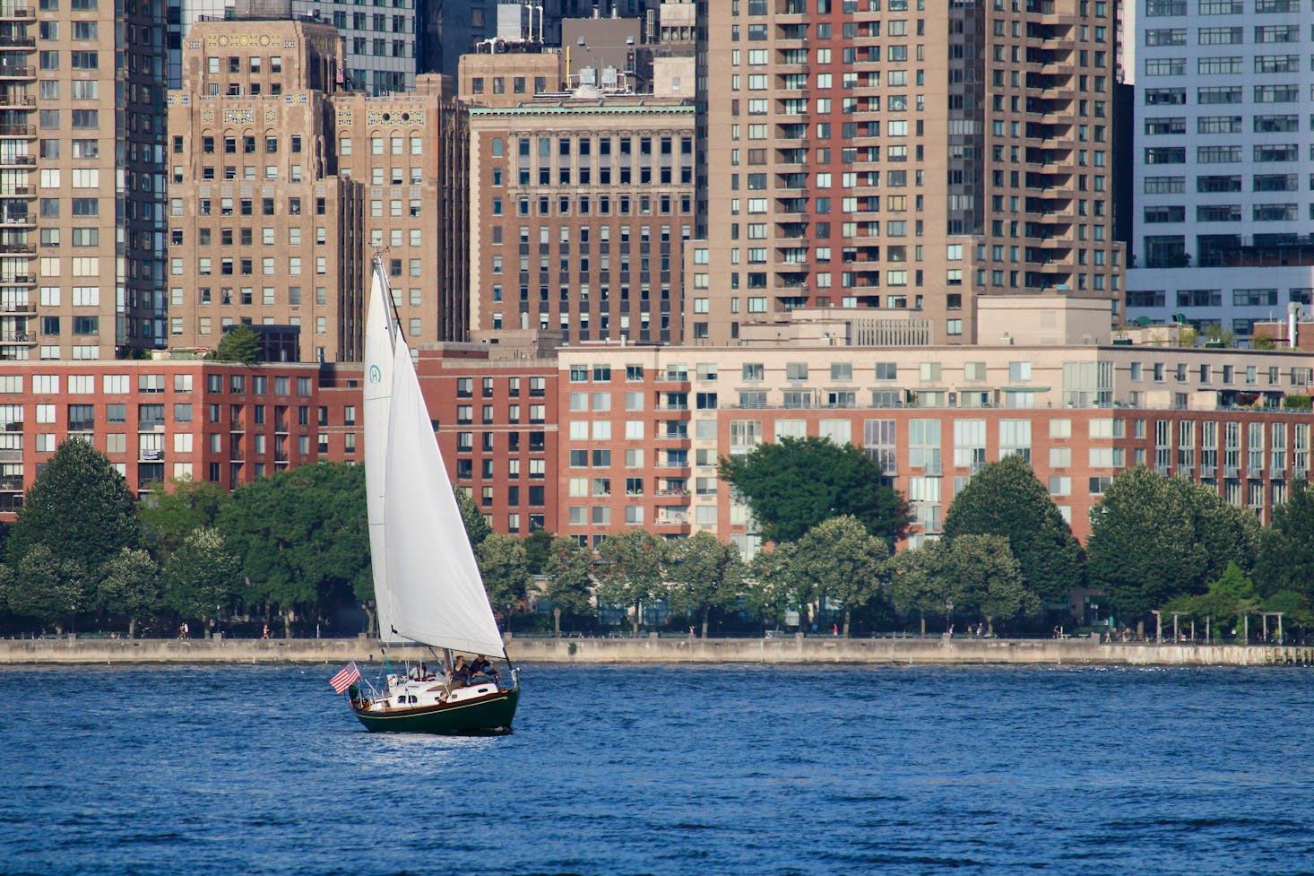 White sail boat on water near city buildings in New Jersey