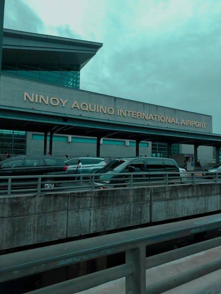 The exterior of Ninoy Aquino International Airport, with cars parked along the drop-off area