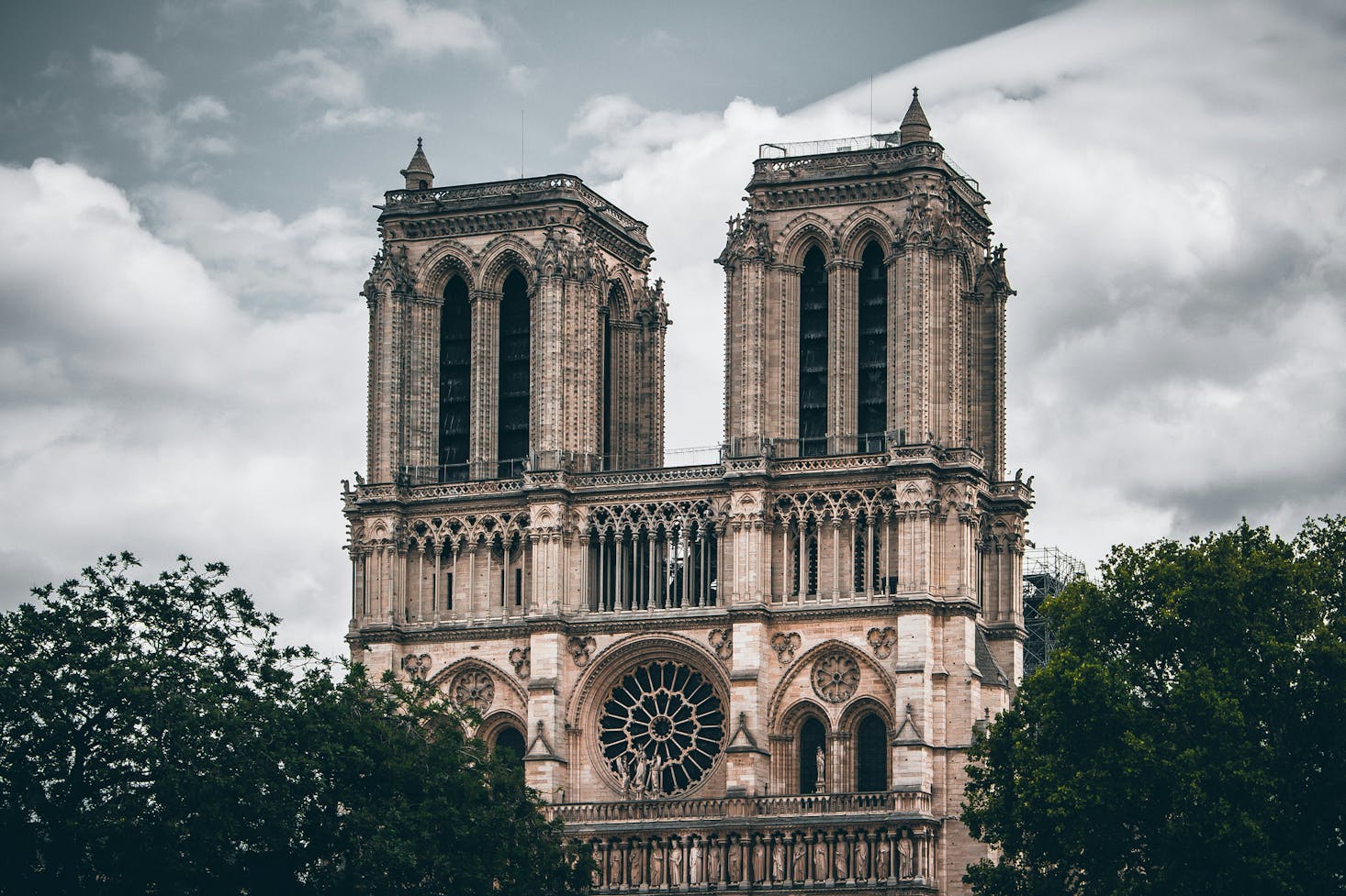 Gothic architecture of the Notre-Dame Cathedral under a cloudy sky.