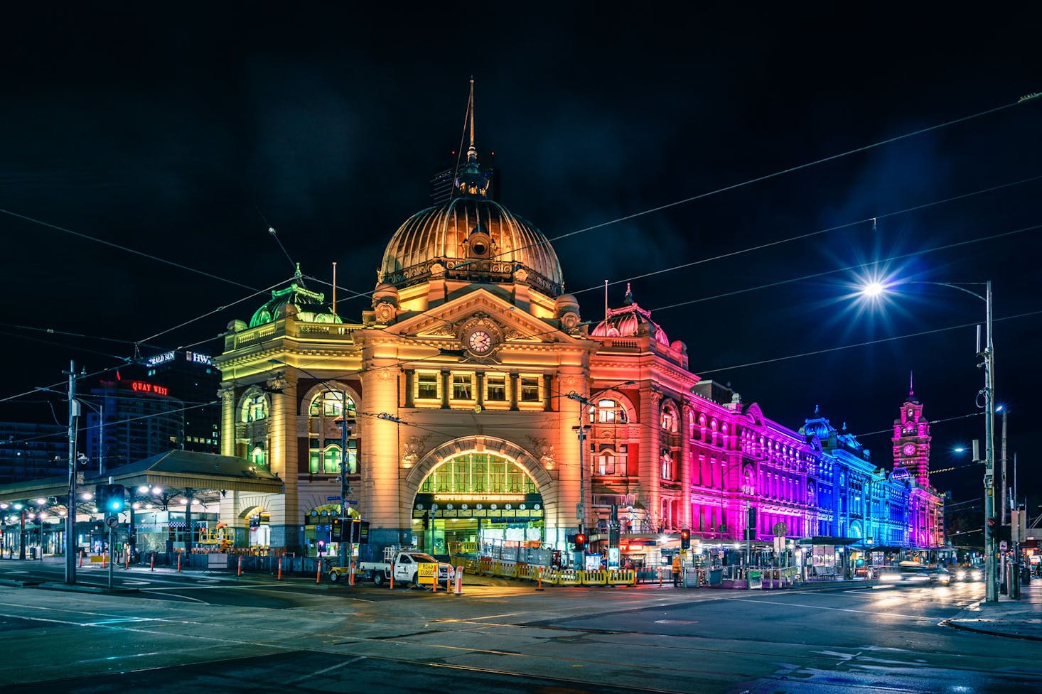 Flinders Street Station in Melbourne, brilliantly illuminated at night with colorful lights