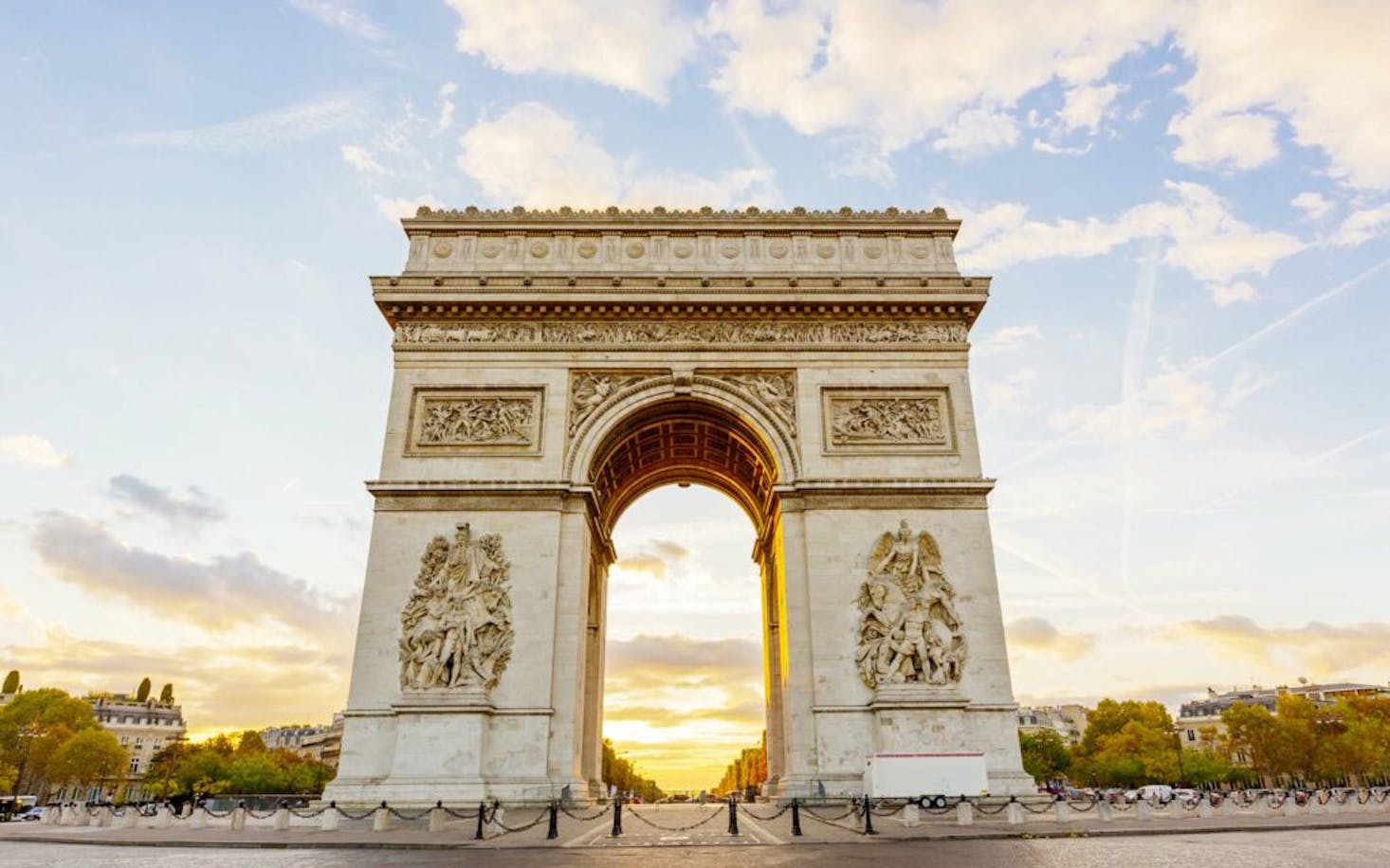 The Arc de Triomphe in Paris, standing majestically against a backdrop of a vibrant sunset sky.