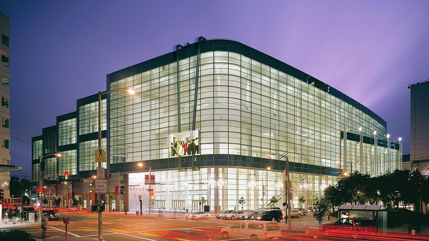 Moscone Convention Center at dusk, with its large glass facade brightly lit from within