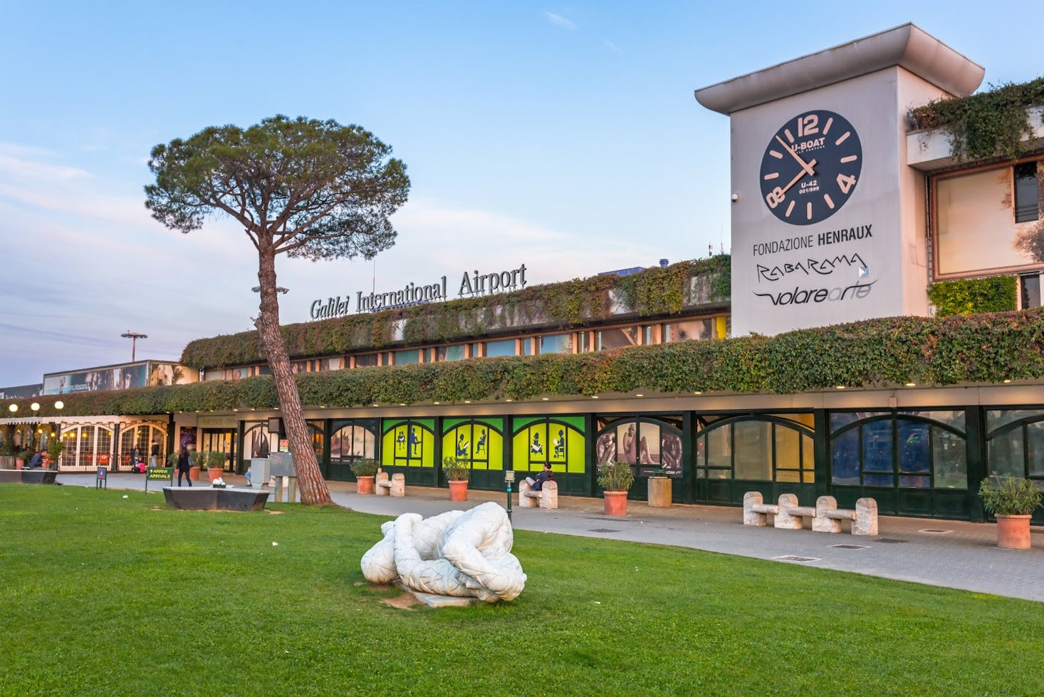 Galileo International Airport in Pisa, featuring a large clock and a green facade.