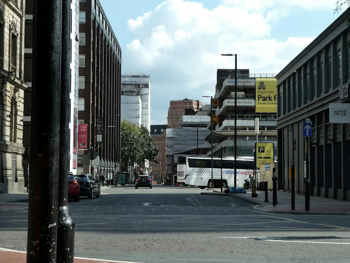 A street view in Manchester, featuring a National Express coach