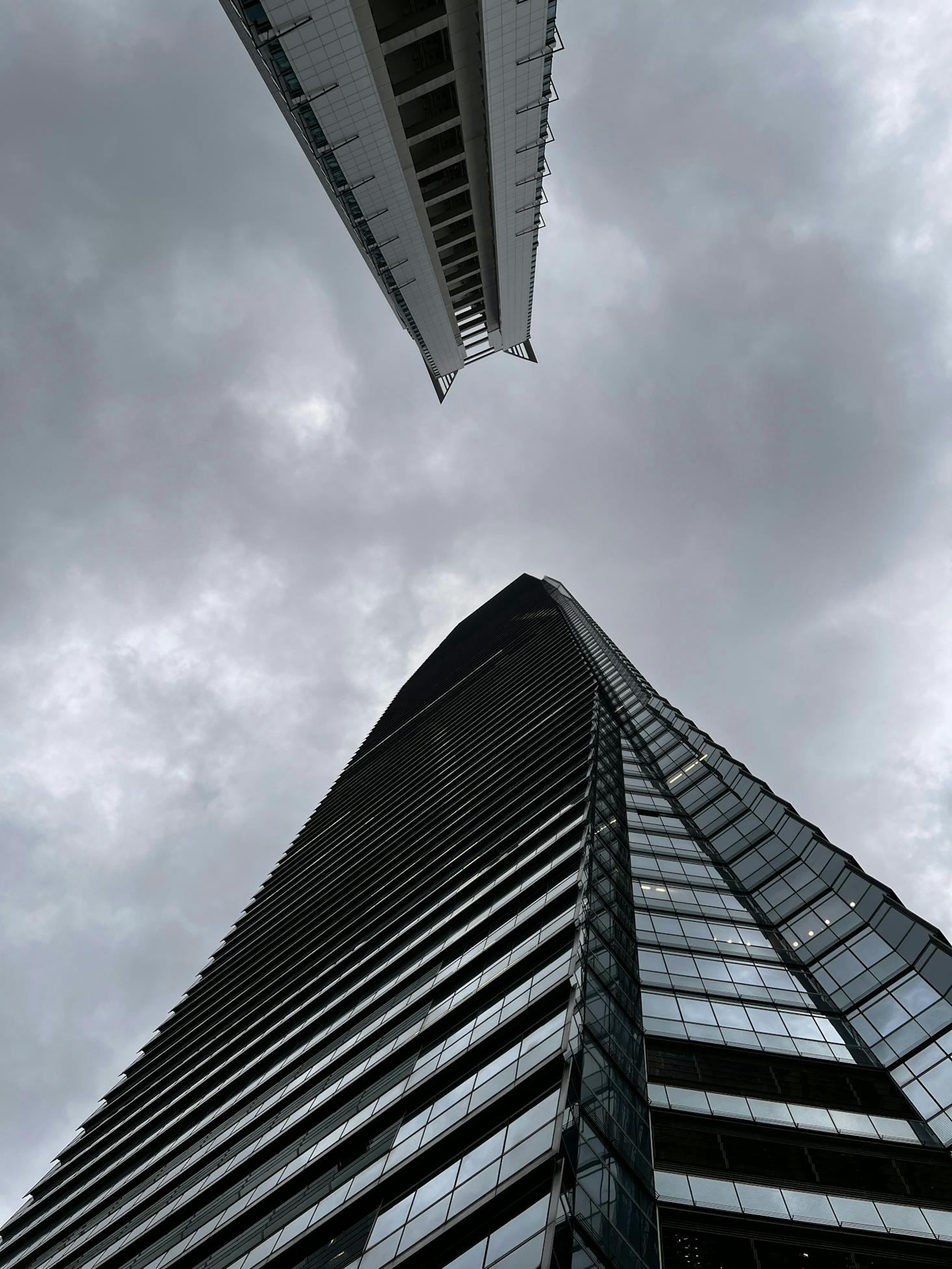 Tall window-filled skyscraper at Kowloon Station, towering into the grey sky