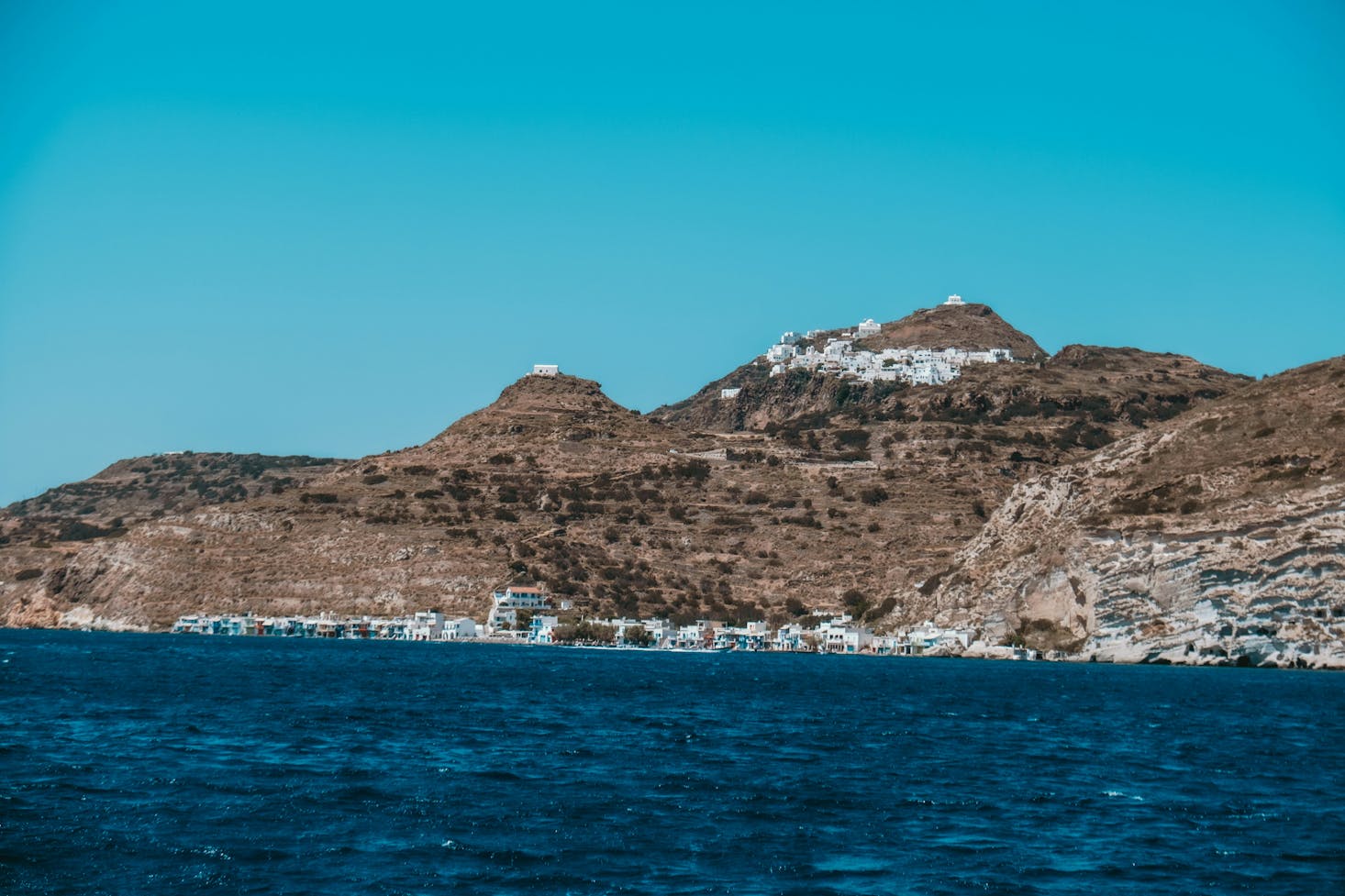 White buildings in Milos, Greece lie close together on the shore of the island