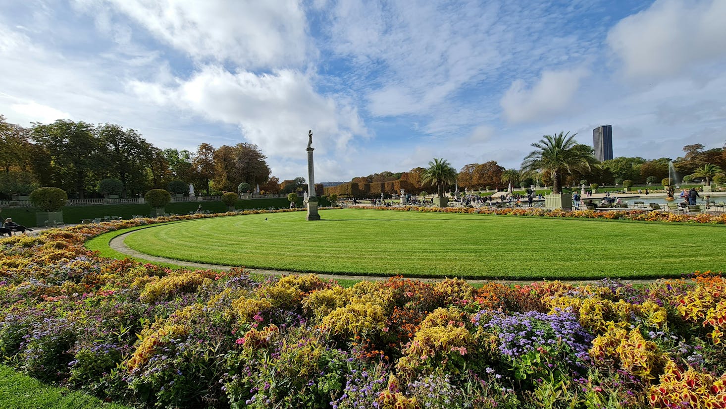 Luxembourg Gardens in Paris with a large green lawn and a thin statue